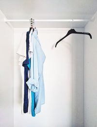 Shirts hanging on coathangers against white wall