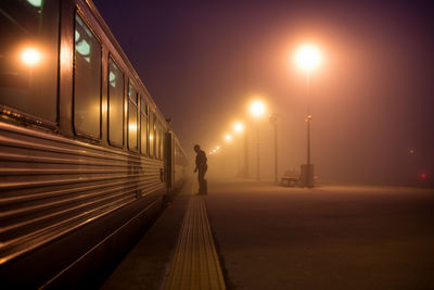 Silhouette man standing by train at railroad station during night