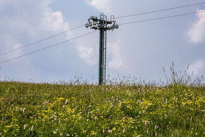 Low angle view of electricity pylon on field against sky