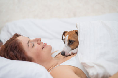 Young woman with dog on bed at home
