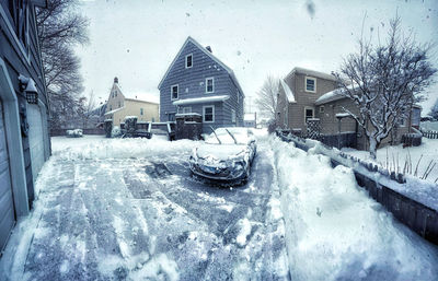 Snow covered houses by building during winter