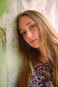 Portrait of young woman standing against wall