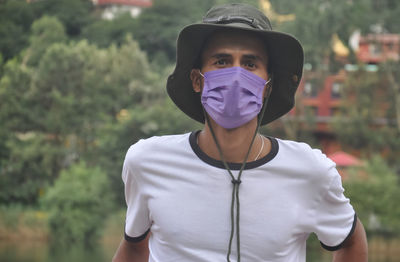 Close-up of a young man standing outside with wearing hat and face mask during covid19