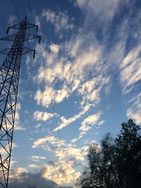 Low angle view of electricity pylon against cloudy sky