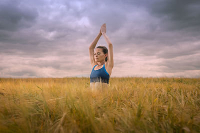 Attractive woman meditating and practicing yoga in a field.