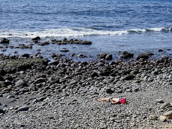 High angle view of woman lying on rock in sea