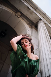 Portrait of young woman standing against wall