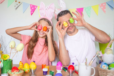 Father and daughter holding easter egg in front of face