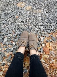 Low section of woman standing on pebbles