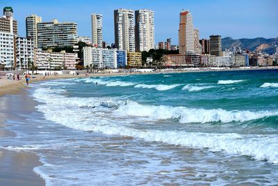 Scenic view of sea with cityscape against cloudy sky