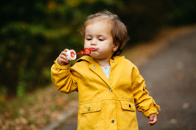 Cute boy holding yellow while standing outdoors