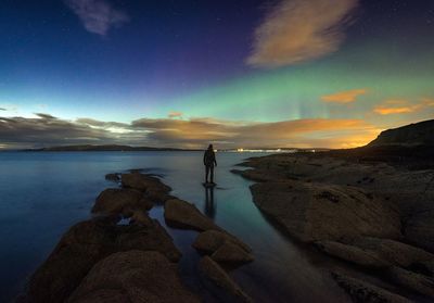 Man photographing sea against sky at night
