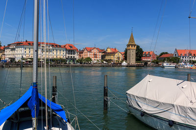 Sailboats moored in canal by buildings against sky in city