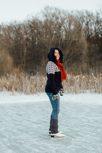 Full length portrait of smiling young woman standing in winter