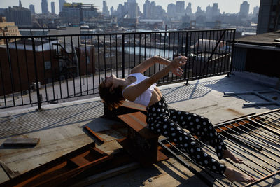 Side view of woman sitting on railing