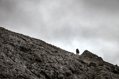 Man standing on rock against sky