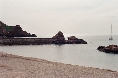 Rock formation on beach against sky