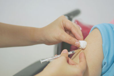 Cropped hands of doctor injecting on patient hand