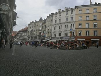 People on street against buildings in city