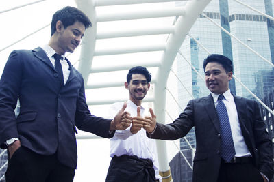 Business colleagues gesturing thumbs up while standing in city