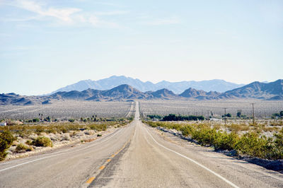 Road leading towards mountains against sky