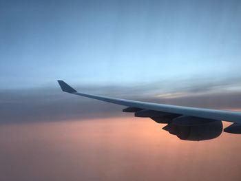 Airplane flying in sky at sunset