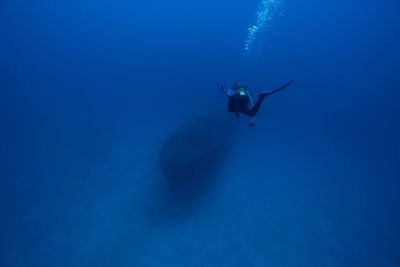 High angle view of scuba diver swimming over ship wreck