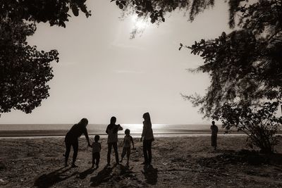 Silhouette people standing on beach against sky