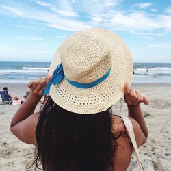 Rear view of woman on beach against sky