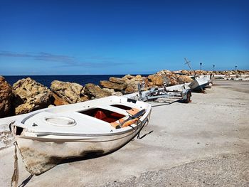 Boats moored on beach against blue sky