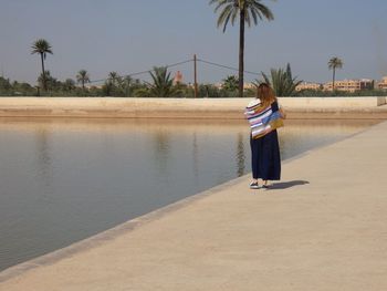 Woman standing at beach against sky