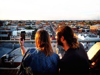 Rear view of people in city against sky