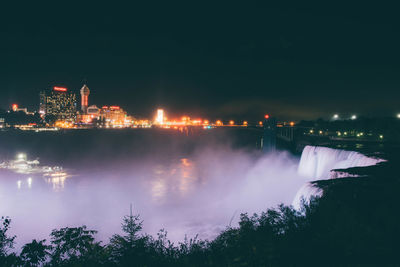 Scenic view of niagara falls in illuminated city at night