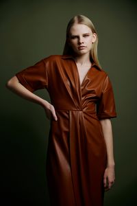 Portrait of young woman standing against wall