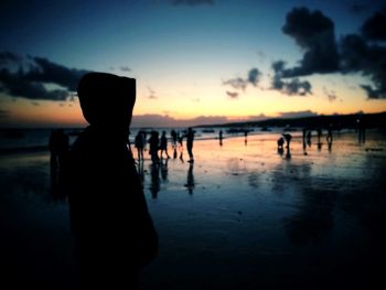 Silhouette people on beach against sky during sunset