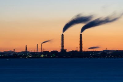 Smoke emitting from chimney against sky at sunset