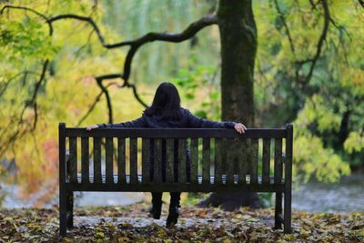 Rear view of woman sitting on bench in park