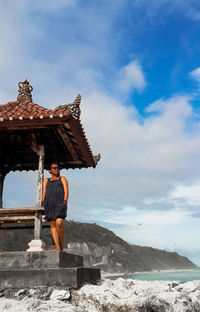 Man standing on rock against sky