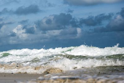 Surface level of waves splashing in sea against sky