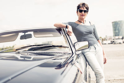 Young man wearing sunglasses standing by car