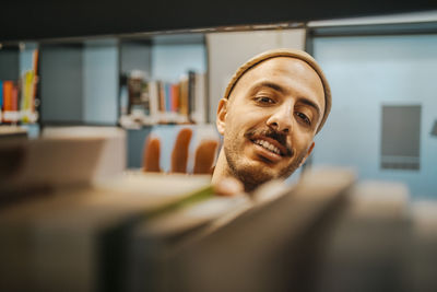 Smiling man searching book in library at university