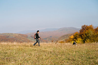 Man with dog hiking in autumn mountains
