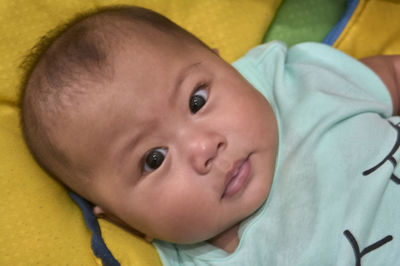 Portrait of cute baby girl lying on bed