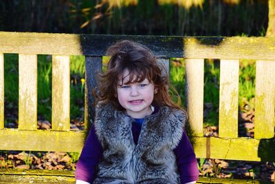 Cute girl sitting on bench while looking away