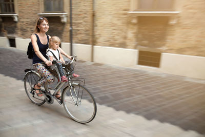 Woman cycling with daughter on footpath