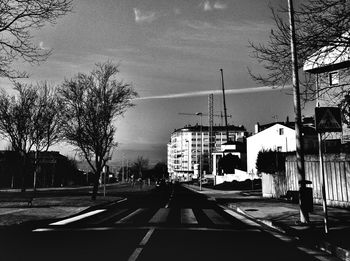 Road by buildings in city against sky