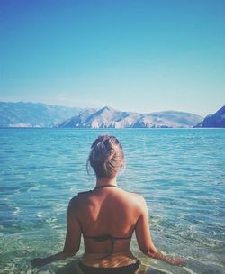 Rear view of shirtless man in sea against clear sky