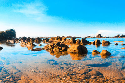 Rocks on shore against blue sky