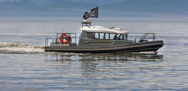 Modern pirates on a motor boat in a bay under a pirate flag