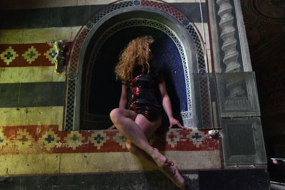 Young woman sitting on door of entrance